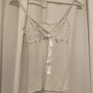 Vitt linne - Ett vitt linne , väldigt söt.  Sitter bekvämt. 95% viskos 5% elastan. Pärldetaljer vid bröst. V-ringad.