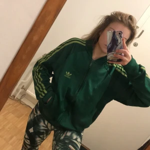 Adidas tröja  - Grön adidas tröjja med ljusgröna stripes.. Den är använd men inga hål eller skador finns. Otroligt bekväm, oversize för mig som är en xs/s. Säljes motvilligt pga flyttstädning.. 