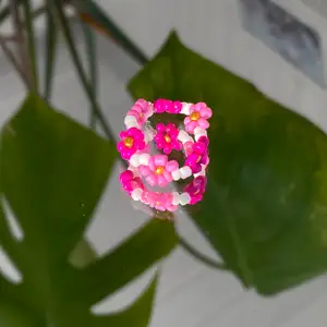 Vit ring med rosa blommor, egentillverkad! 💗                   Passar S                                                                         Säljer för 20kr + 12kr i frakt. Fraktpriset är det samma oavsett antalet ringar man köper ✨