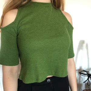 Grön t-shirt från Monki - Croppad grön t-shirt från Monki med cut-out på axlarna. Skön med bra passform. Säljes endast för att jag inte använder den längre.