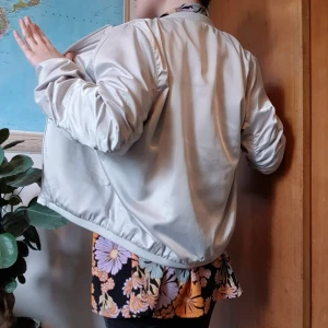 Beige bomberjacka - Beige luftig bomberjacka. Den är tunn och därmed perfekt när det inte är så kallt ute men man ändå vill ha något som skyddar mot blåsten.