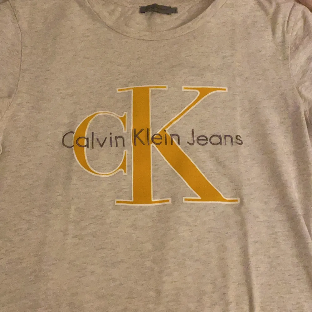 Calvin Klein t-shirt. Typ grå vit med gult, vit, gråt tryck . T-shirts.