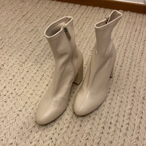 Stövletter - Helt nya! Benvita stövletter från Bershka med en klackhöjd på ca 6cm. Sitter smickrande tajt på ankeln och matchas fint både med klänning och byxa. Skon är i strl 36. Ovandelen är i skinnimitation.