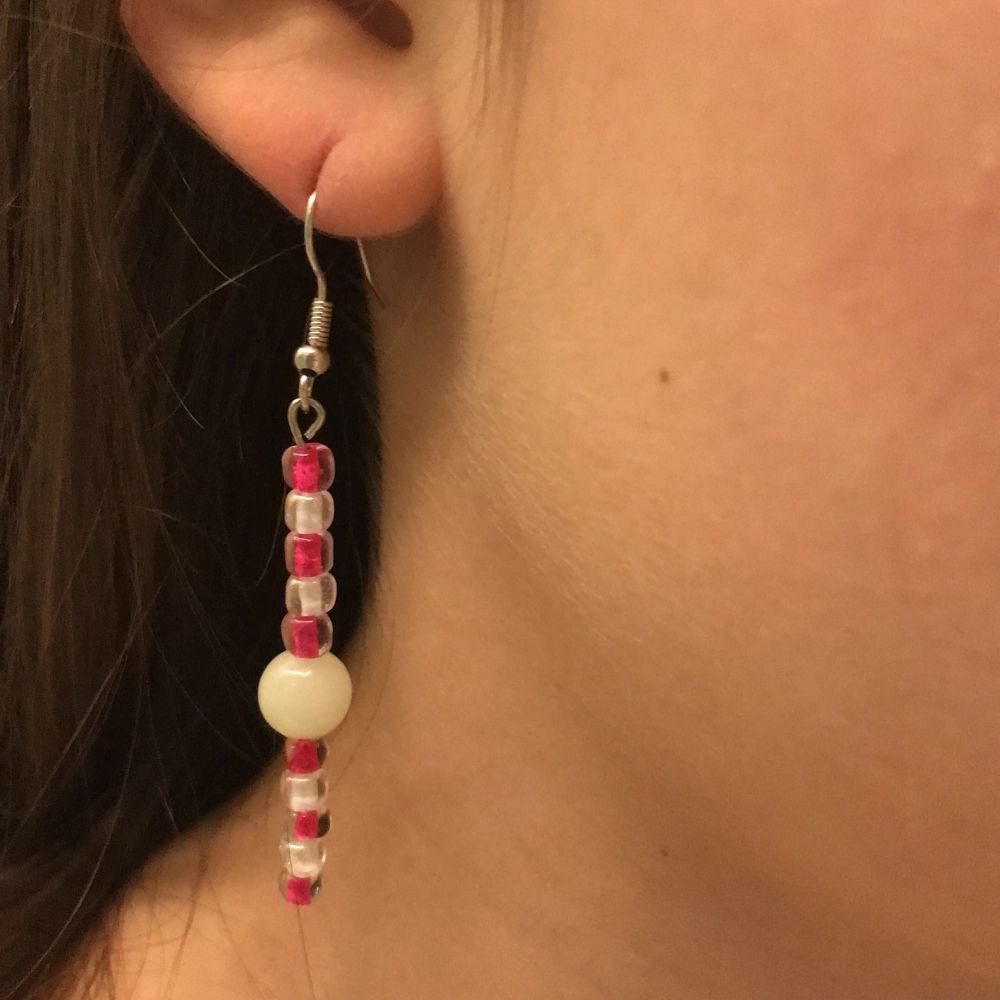 Detta är ett par örhängen som innehåller en självlysande pärla och några andra rosa och vita. På sista bulldeg så måste du dra upp ljusstyrkan på telefonen för att se. Men det är när pärlorna lyser i mörkret!. Accessoarer.