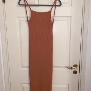 Lång klänning med öppen rygg - Oanvänd laxfärgad tajt klänning, klänningen är lång till knäna, öppen vid ryggen.