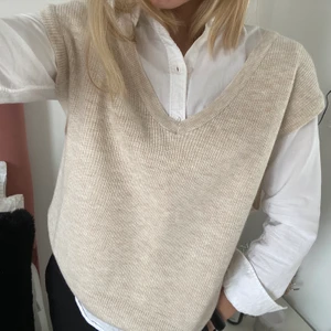 Stickad väst - Stickad väst med urringning. Jättefin över en skjorta eller bara som den är. Lite stor i storleken. Köpt på stradivarius.