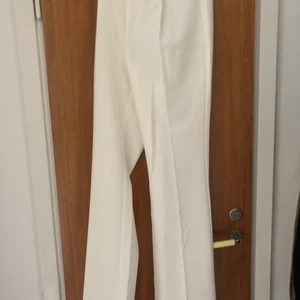 Kostymbyxor i vit stl 36 - Långa kostymbyxor prefekt till studenten. Aldrig använt, är perfekta för studenten då det är långa vita kostymbyxor. Är långa även för någon runt 175 cm lång. Har en dragkedja och inga fickor bak.