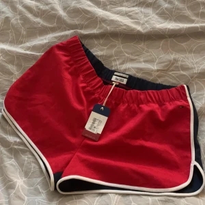 Hilfiger Denim  - Ett par riktigt snygga Hilfiger shorts i storlek L, funkar på en M också beroende på hur man vill att dom ska sitta. Helt oanvända med prislapp kvar, nypris på dessa är 998. Röd fram & mörk blå bak. 