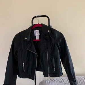 Skinnjacka barnkläder  - Skinnjacka i storlek 146 från Lindex. Aldrig använd och är i topp skick. Köpt för 400kr säljer den för 200kr. Köparen står för frakten!