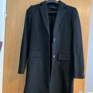 Svart basic kappa från ZARA  - En jättefin basic svart kappa från ZARA köpt förra hösten och aldrig använd. Den är rak och klassisk i modellen. Nyskick. Bilderna gör sig inte helt rättvisa. Storlek 34. Köpt för 1200kr. Perfekt höst och vårkappa och även vinter, med en tunn funktionsjacka under. Pris kan diskuteras vid snabb affär 