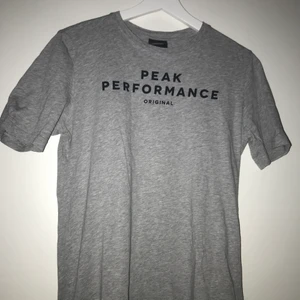 Peak Performance t-shirt strl. XS/S - En grå Peak Performance T-Shirt i storlek XS/S. Svart tryck mitt på bröstet. 