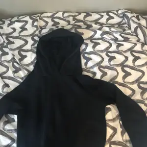 En svart hoodie, tyvärr har det ett hål i armen vilket gör att den ligger på ett lågt pris