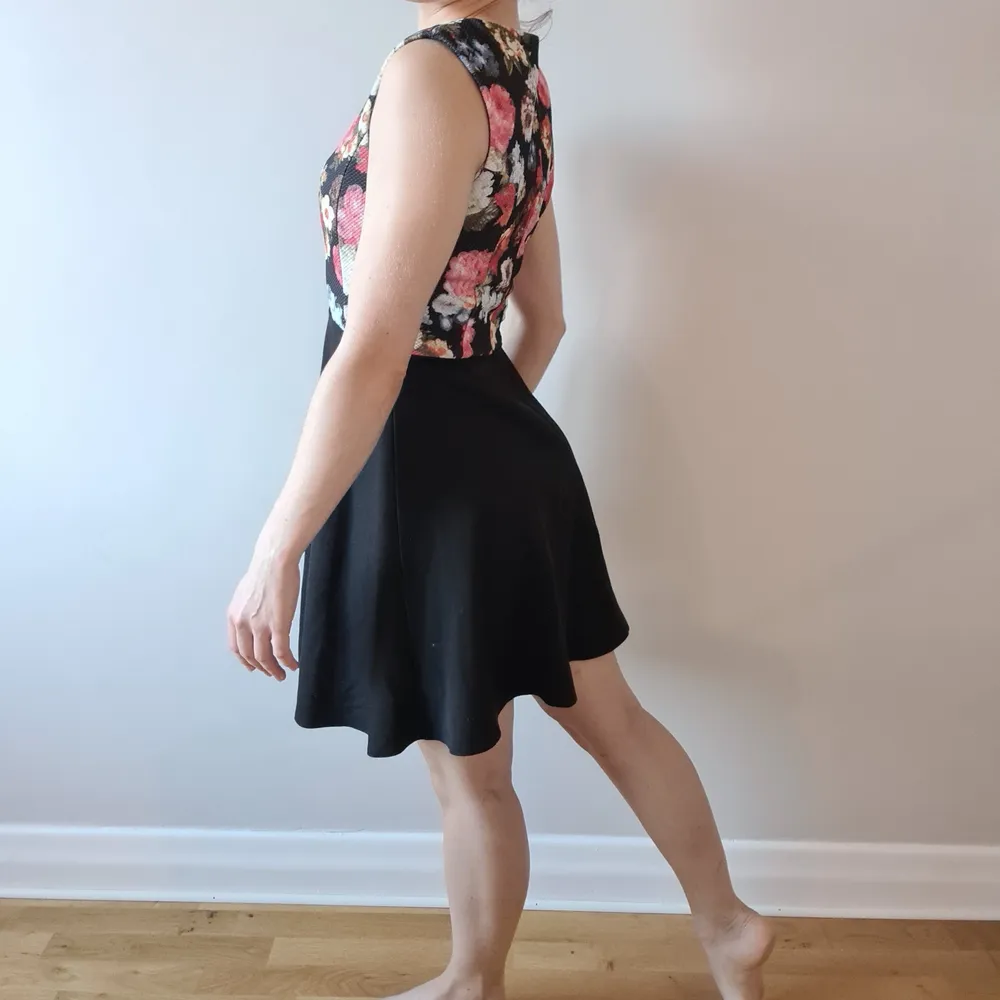 Superskön klänning, med blommig överdel, figursmickrande sömmar och svart böljande kjol. Dragkedja i ryggen (syns på 3e bilden).. Klänningar.
