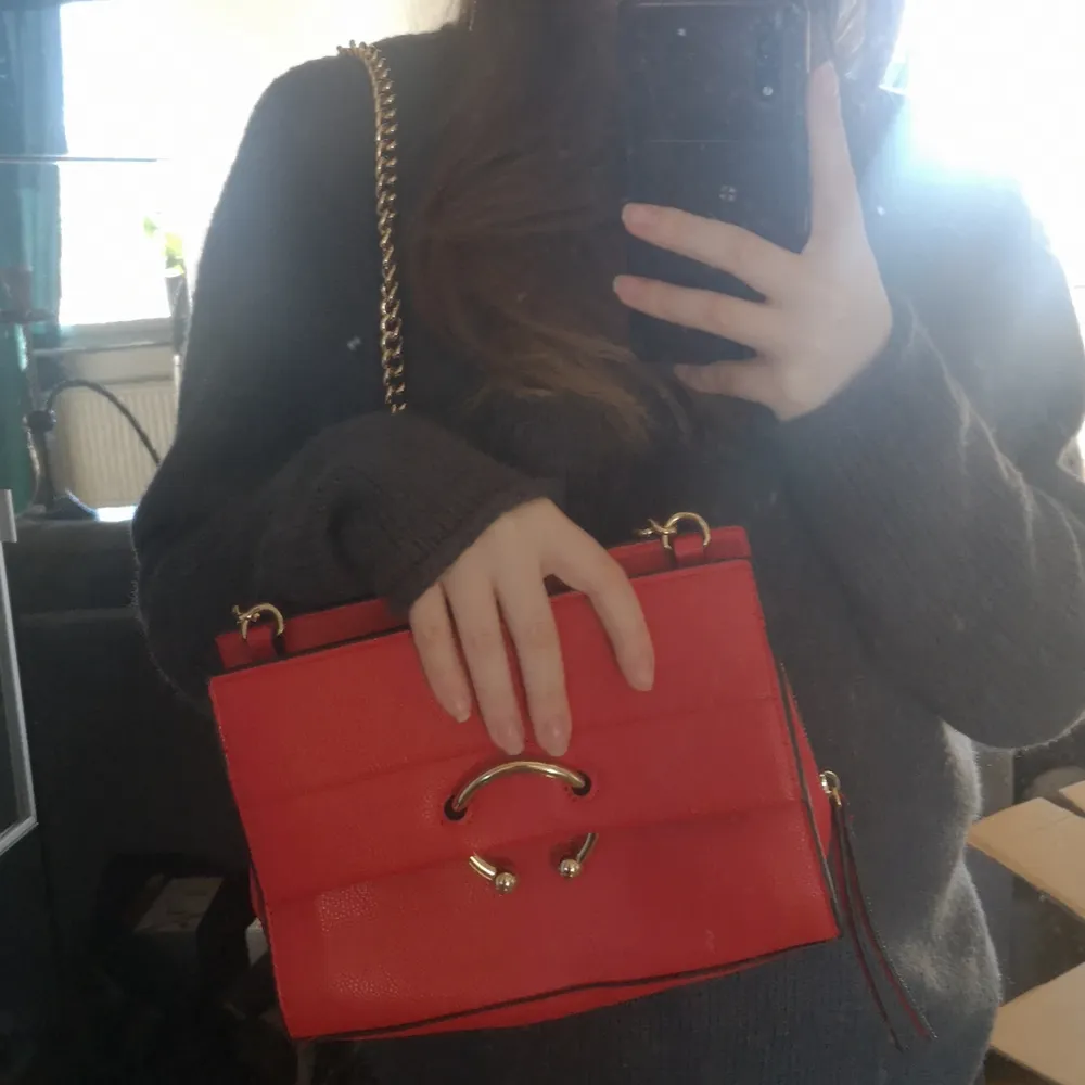 En liten röd handväska med dragkedjan . Väskor.