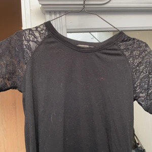 Svart T shirt med spets detaljer  - Svart t shirt med spets detaljer på ärmarna i bra skick från vero Moda. Funkar till både vardag och finare tillfällen