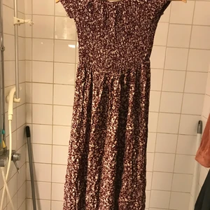 Sommarklänning - En flowy sommarklänning i en dov vinröd ton med vita små blommor, rysch upptill och ärmar för en offshoulder passform:)