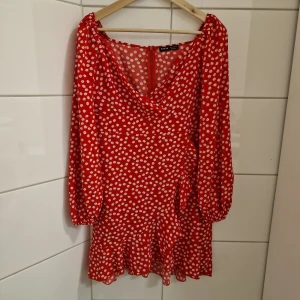 Småblommig klänning (Nyskick) Strl M - Klänning  Strl M Nyskick! Färg: Röd, Vit Shein  Underbar kort klänning i omlottmodell med volangdetaljer. Småblommigt mönster. Dold dragkedja i ryggen. Endast använd en gång.