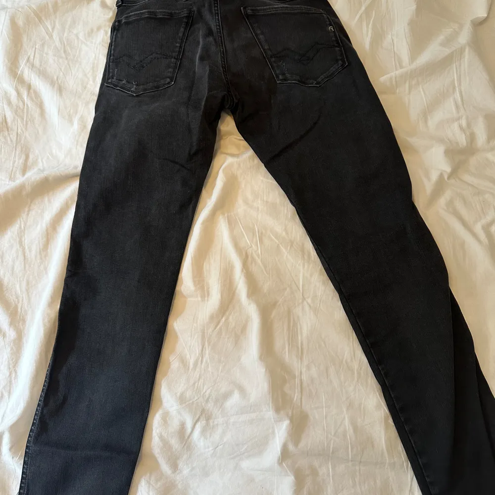 Ett par svarta jeans från Replay i modellen Anbass. Jeansen har en smal passform och är tillverkade i ett stretchigt material för extra komfort. De har en klassisk femficksdesign och är dekorerade med diskreta slitningar på framsidan. Helt nya utan prislapp!. Jeans & Byxor.