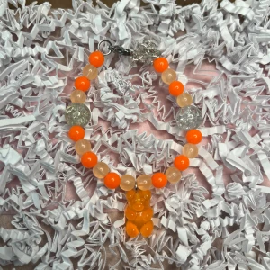  Orange armband med berlock - Orange armband med berlock som går att justera.