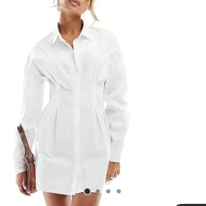 Vit mini-skjortklänning  - Säljer denna fina skjortklänning med indragen midja. Klänningen är köpt från Asos, aldrig använd och prislappen sitter kvar.(slutsåld i alla storlekar på hemsidan). Säljer pga för liten för mig och för sent för en retur🌸 Nypris 509kr