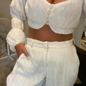 Vitt sommarset - Säljer nu detta OTROLIGA set från Angelina Blick x NAKD kollektion (byxor och tröja). Byxorna är långa på mig (165cm). Köpte settet second hand och märkte att kedjan vid gylfen kan åka ner men kan säkert fixas med en nycelring man fäster i gylfen. 