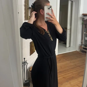 Michael Kors klänning  - En marinblå Michael Kors klänning med gulddetaljer. Mycket bra skick förutom ett guldhänge som lostnat. Klänningen går till låren på mig och jag är 167 cm. Liten i storlek. 