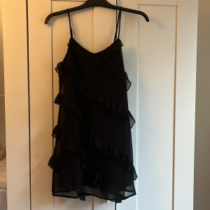Svart volang klänning - Säljer denna svarta volang klänningen ifrån gina tricot! Den är i storlek 158/164 och har använts 2-3 ggr! Skriv om ni vill ha bilder på hur den ser ut på. Tror inte den finns kvar längre❤️