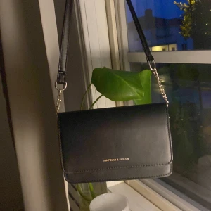 Svart väska - Aldrig använd  För att använda som kort axelväska behöver man snurra ihop kedjan som på bilden. Kan nog gå att förkorta permanent genom att fixa lite.