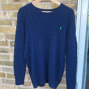 Kavelstickad tröja - Säljer denna klassiska kavelstickade tröja från Ralph Lauren då jag personligen inte använder den, Ralph Lauren märket är grönt och resten av tröja marinblå. Sparsamt använd, skulle säga att den sitter som en S