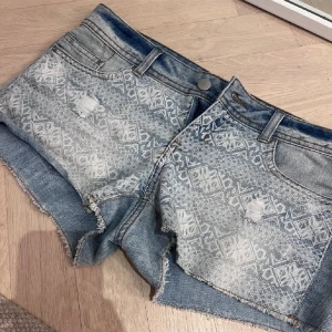 Lågmidjade jeansshorts med vitt mönster  - Jättesöta Lågmidjade jeansshorts med vitt mönster, storlek 38 men skulle säga att de är 36-38. Midjemått rakt över är 40cm🌸