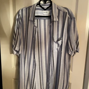 Randig kortärmad skjorta - Väldigt skön och schysst skjorta till sommaren och jag hade haft den men tyvärr lite stor men det känns som att man inte har på sig något den här med ett par linnebyxor är perfekt till dig nu när vädret blir bra. Den är knappt använd bara någon gång.