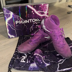 Fotbollskor Limited Edition Phantom Luna Elite Thunder Fuchsia Dream - Storlek 44. Shoebag och box medföljer. Skick 9/10, inte använt mycket, ända är en liten grej längst fram på vänster sko (sista bilden) och att snörena blivit lite fransiga. Nypris 3349kr 