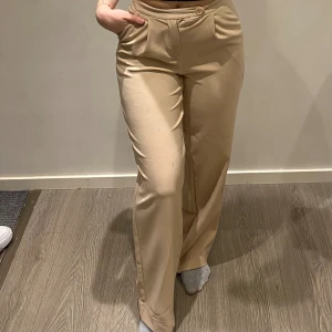 Kostymbyxa - Detta är en jätte fin kostym byxa som funkar till allt. Sitter as fint på kroppen den formar verkligen på sättet ens kropp är på vilket är vackert. En jätte fin beige färg, inte alldeles för lång då jag är 160cm