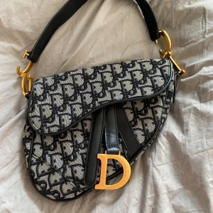 CD  - CD partyväska saddlebag. i tyg i monogram helsydd. Invändig monogram silketyg med innerficka. 
