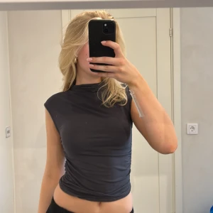 Grå festtopp  - Jättsnygg mörkgrå tajt festtopp från Gina tricot. Storleken är s men passar även Xs. Har knappt används och har inga defekter alls 💗