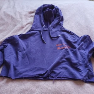 Kropad hoodie strl M - En lila kropad hoodie som slutar över naveln i strl M från H&M. Den har en orange drake samt lite orange text på armarna/bröstet. Lite trådad oxå men det tillhör modellen. Väldigt lite använd