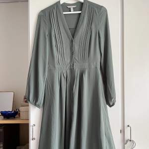 Grågrön klänning i tunnt tyg från H&M. Aldrig använd. Passar både xs och s, under knäna/mitt på vaderna på mig som är knappt 170. 