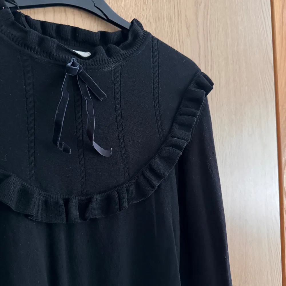 En svart broderad tröja med en rosett i mjukt tyg. Rik på detaljer i både ärmar och på bröstet. . Blusar.