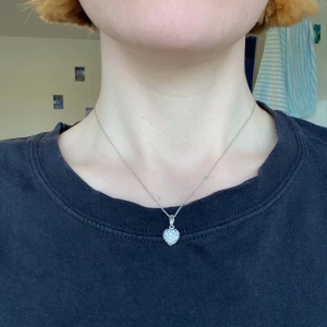 Silvrigt halsband - Silvrigt halsbans med hjärtbärlock. Knutan på kedjan är löst. Matchande örhängen finns!