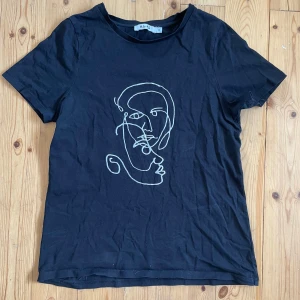 NA-KD tshirt - Säljer denna svarta t-shirt med ett fint tryck. Den är använd men utan tecken på användning. Storleken är XS och den är från NA-KD. Hör gärna av dig vid frågor!💞