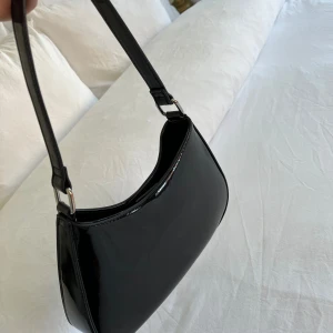 Väska Gina Trocot - Liten väska från Gina Tricot.  Endast använd vid ett tillfälle.. stängs med ett knäppe på insidan och finns även ett fack med dragkedja i väskan. 