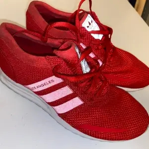 Röda adidas skor strecken är vita, blev rosa av blixten. 