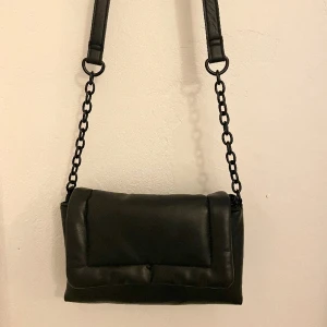 Svart Axelbandsväska  - Svart väska med fina detaljer! 22x14cm  Köparen står för frakten. 