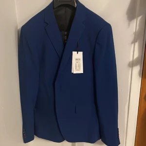 Blå kostym (helset) - Helt oanvänd kostym i slim fit passform. Nypris 1499, storlek 50 (liten i storleken)