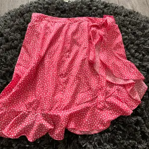 Kjolen är mer skrik rosa, den är inte röd som den ser ut på bilden. Gick inte o få den riktiga färgen på bild, men den är mer rosa. Jättefin omlott kjol, aldrig använd. Man knyter den.
