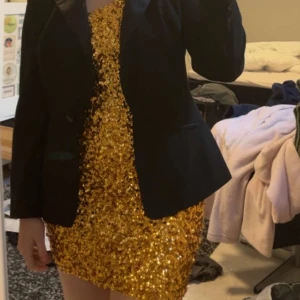 Guldglittrande klänning - Säljer min snygga och coola klänning som jag hade tänkt ha på en fest med discotema. Men den blev aldrig använd. Köpt på NA-KD är jag rätt säker på för ca 1,5år sedan så den finns inte kvar på hemsidan tyvärr. Men den är oanvänd.