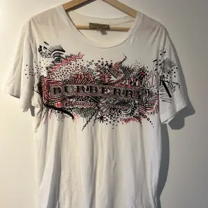 Vit Burberry t-shirt av skön kvalitet med tryck. Storlek S, passar som M/L. Plagget är i bra skick. Pris: 399kr. Vid frågor, kom PM!