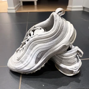 Nike air Max 97 - Nike air Max 97 i vit färg.   Nypris 2299 kr.  Strl 38.   Liten repa på bild 3, där reflexerna är - därav priset   Annars bra skick