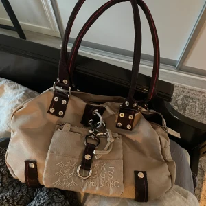 Y2k george, Gina and lucy väska - En handväska från G,G&L (george, Gina and lucy). Jättefint skick, i princip ny. Jag har knappt använt den. Det finns 3 stora fack och 6 ytterligare små. Skicka gärna meddelande vid frågor. Tack för titten!