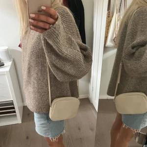 Axelremsväska  - Gullig axelremsväska, färgen är benvit